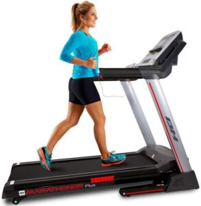 Mujer de pelo castaño con camiseta azul corriendo en una cinta de la marca BH